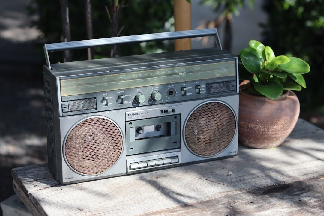Vanha c-kasettisoitin ja radio puisella pöydällä kasvin vieressä