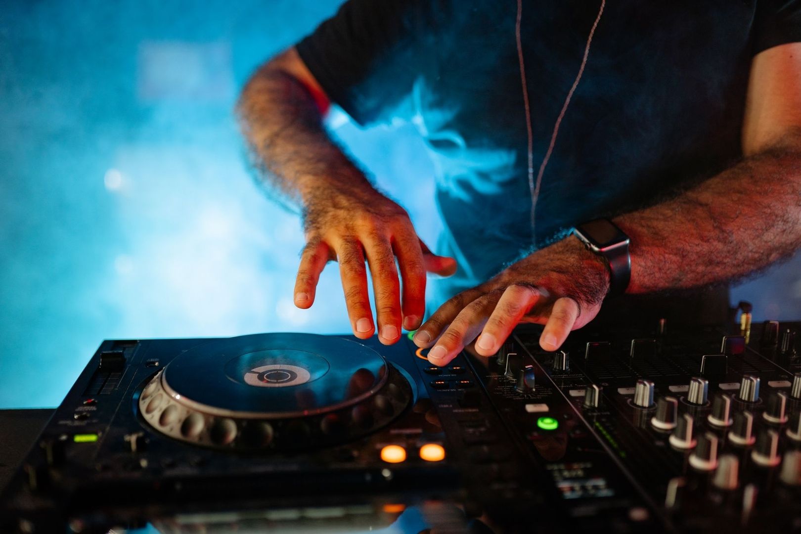 DJ säätää vinyylisoitinta ja mikseriä sinisessä valaistuksessa